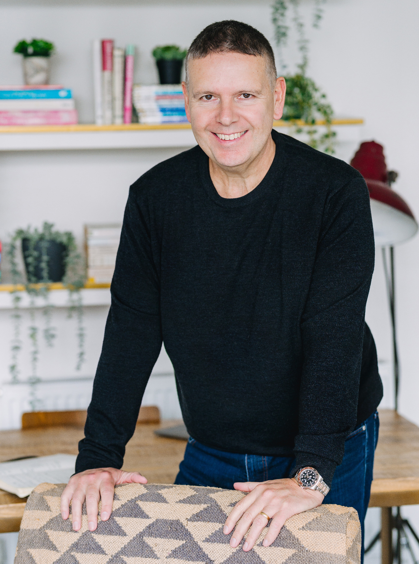 Steve Matthews smiling, leaning on a chair in his studio